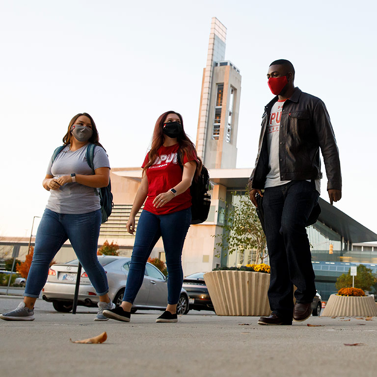Students wearing masks walk on campus.